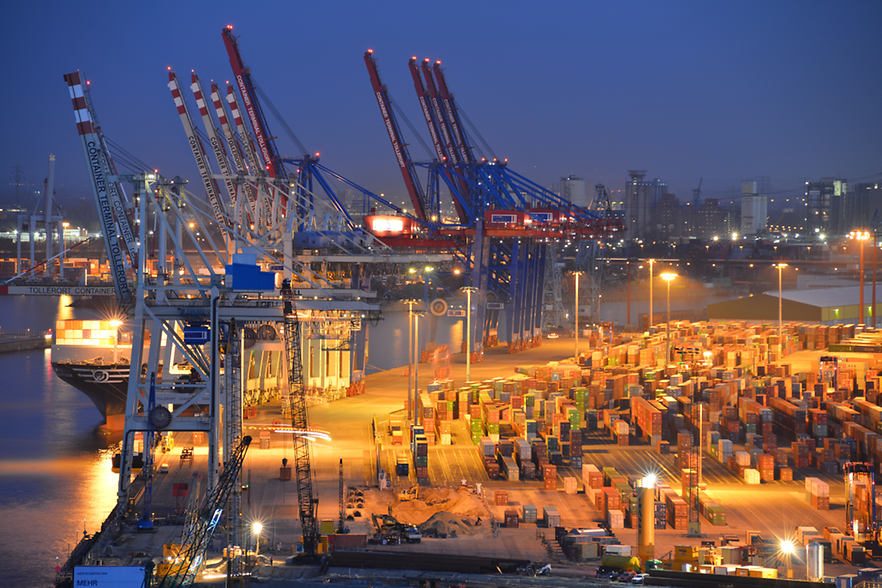 Containerschiff am Kai, gelagerte Container am Hafen (nächtliche Beleuchtung)