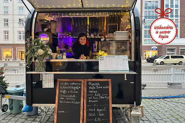 Eine Frau steht in einem Verkaufsstand auf dem Weihnachtsmarkt.